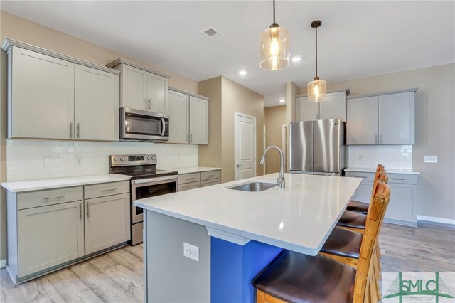 kitchen featuring gray cabinetry, sink, light hardwood / wood-style flooring, and stainless steel appliances