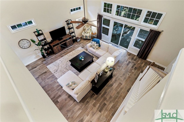 living room with wood-type flooring, a high ceiling, and ceiling fan