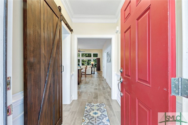 entryway featuring a barn door, crown molding, and light hardwood / wood-style floors