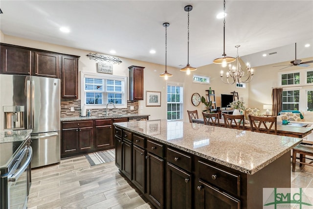 kitchen with ceiling fan with notable chandelier, decorative light fixtures, plenty of natural light, and a kitchen island