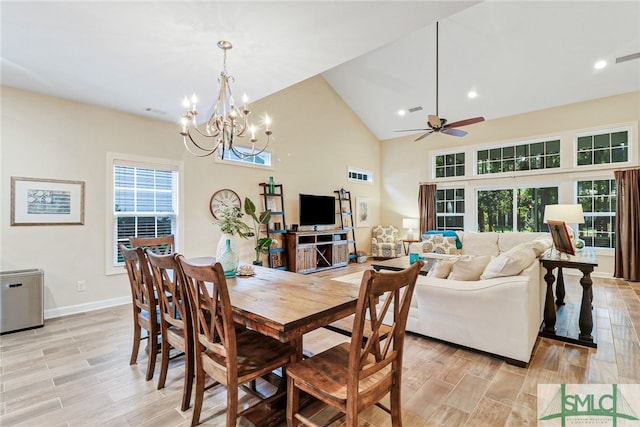 dining room featuring ceiling fan with notable chandelier, light hardwood / wood-style flooring, and high vaulted ceiling