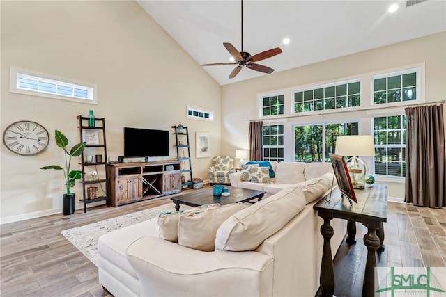 living room featuring high vaulted ceiling, light wood-type flooring, ceiling fan, and plenty of natural light