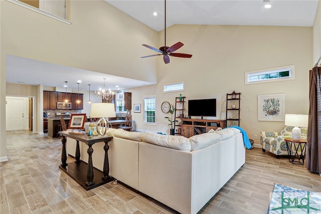 living room featuring high vaulted ceiling, light hardwood / wood-style flooring, and ceiling fan with notable chandelier