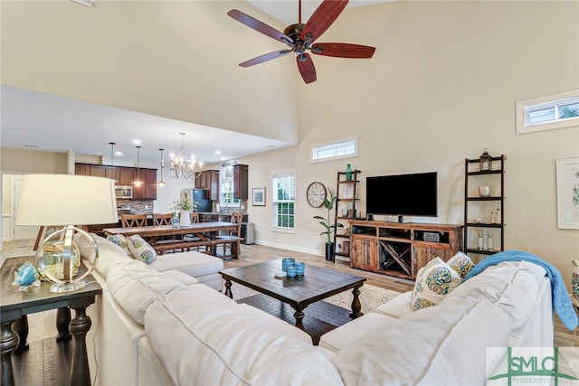 living room with ceiling fan with notable chandelier, light hardwood / wood-style flooring, and plenty of natural light