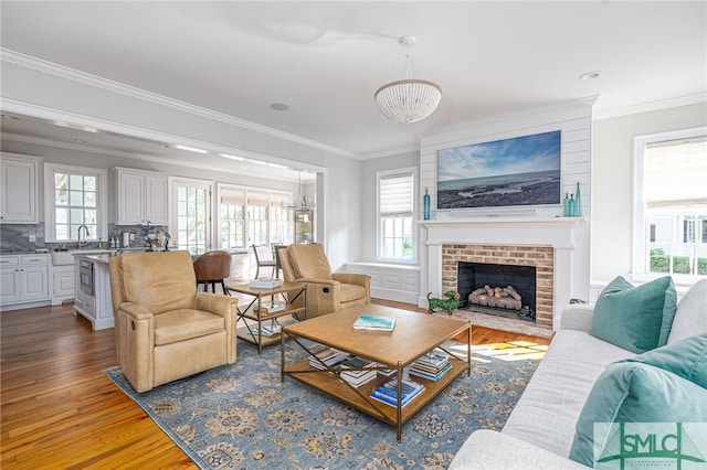 living room with a wealth of natural light, a chandelier, light hardwood / wood-style floors, and a fireplace