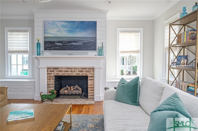 living room with crown molding, a wealth of natural light, a brick fireplace, and hardwood / wood-style flooring