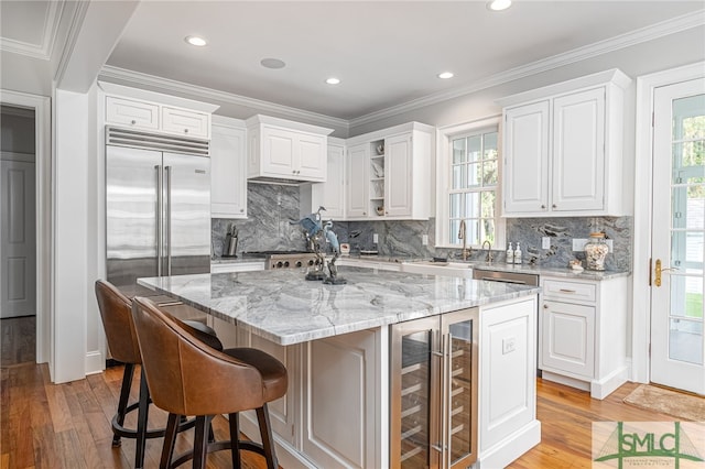 kitchen featuring light hardwood / wood-style flooring, wine cooler, light stone counters, and a kitchen island