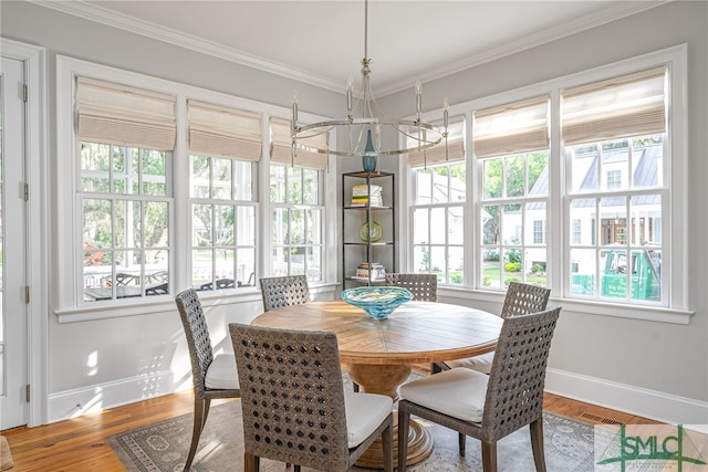 dining area with wood-type flooring, ornamental molding, and an inviting chandelier