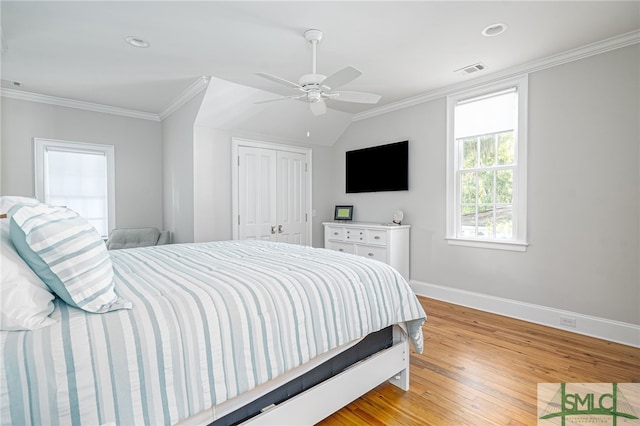 bedroom with light wood-type flooring, crown molding, ceiling fan, and a closet