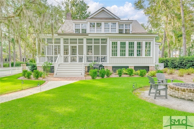 back of house with a lawn, a sunroom, and a fire pit