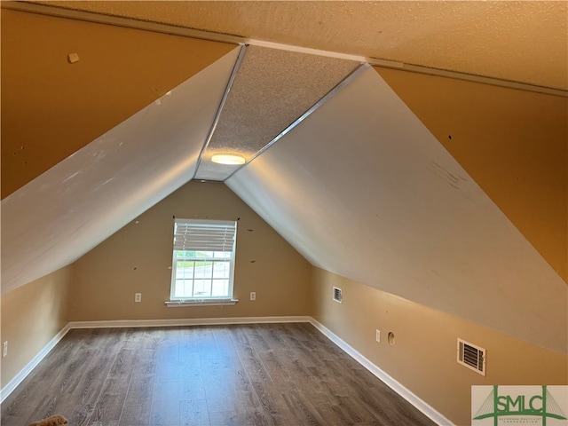 bonus room featuring vaulted ceiling, hardwood / wood-style flooring, and a textured ceiling