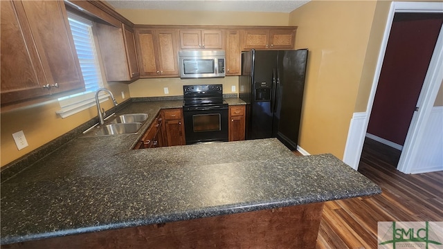 kitchen featuring dark wood-type flooring, sink, black appliances, and kitchen peninsula