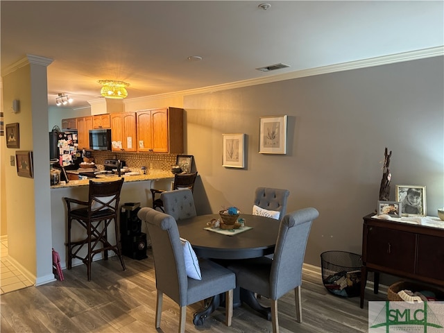 dining area with crown molding and dark wood-type flooring