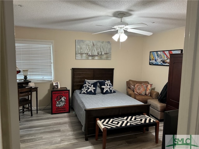 bedroom featuring ceiling fan, hardwood / wood-style floors, and a textured ceiling