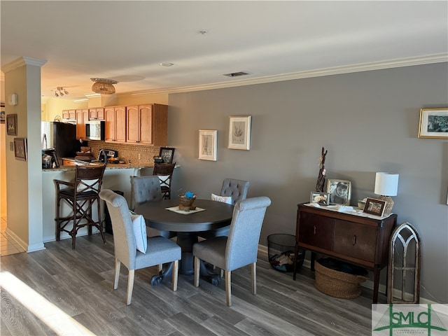 dining space with dark hardwood / wood-style flooring and ornamental molding