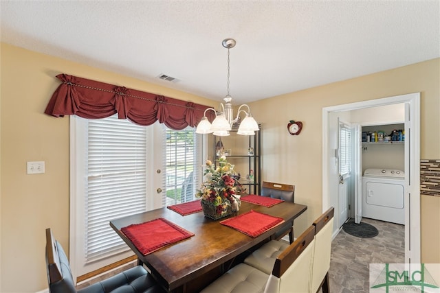 dining area featuring a chandelier, washer / clothes dryer, and a textured ceiling