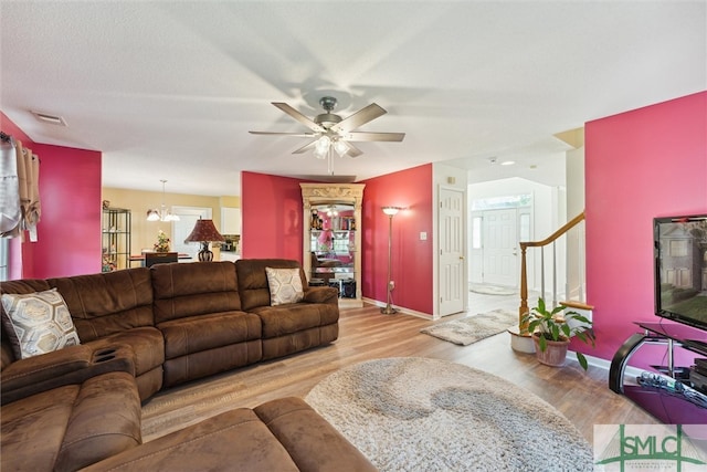 living room featuring a textured ceiling, ceiling fan with notable chandelier, and light hardwood / wood-style floors