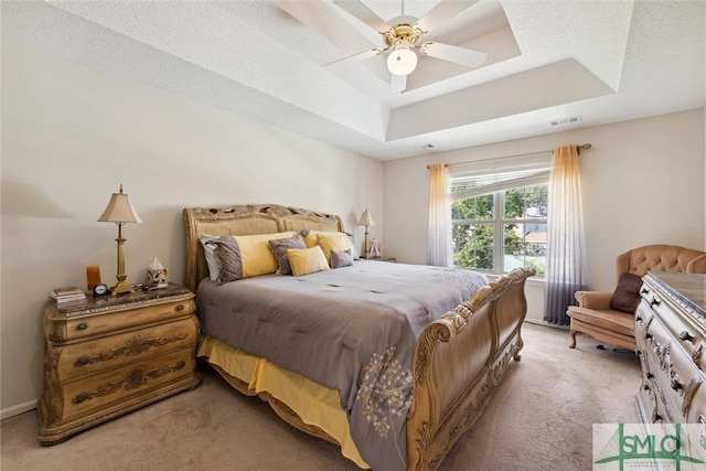 carpeted bedroom with a tray ceiling and ceiling fan