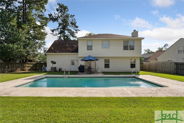 back of property with a fenced in pool, a patio, and a yard