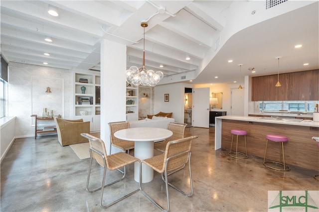 dining area with a chandelier, built in features, and concrete floors