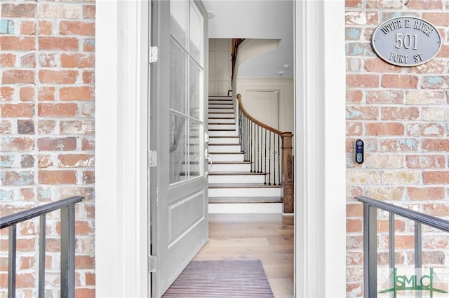 staircase featuring hardwood / wood-style flooring and brick wall