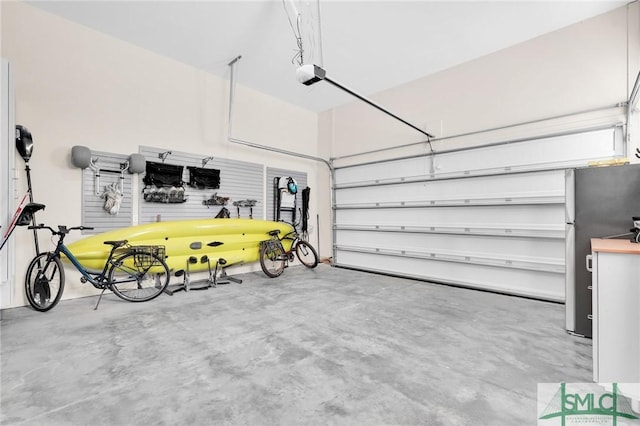 garage with stainless steel refrigerator and a garage door opener