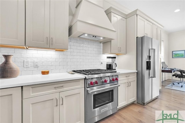 kitchen with backsplash, custom exhaust hood, light hardwood / wood-style floors, and stainless steel appliances