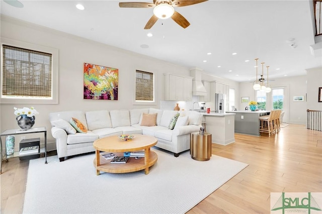 living room with ceiling fan, light wood-type flooring, and sink