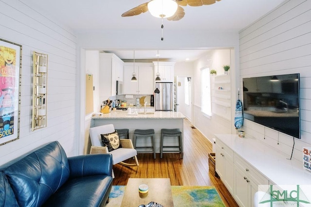 living area with wood finished floors, wood walls, and ceiling fan