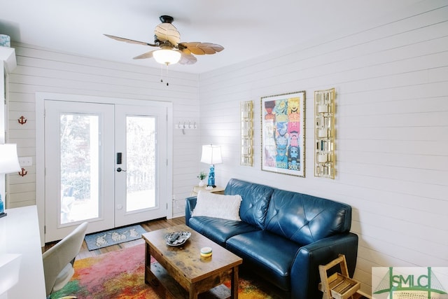 living room with wooden walls, hardwood / wood-style floors, ceiling fan, and plenty of natural light