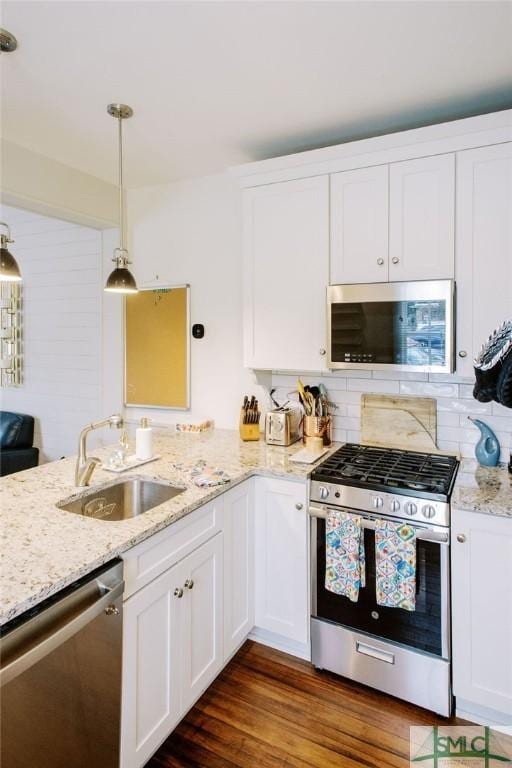kitchen with stainless steel appliances, a sink, decorative backsplash, a peninsula, and white cabinetry