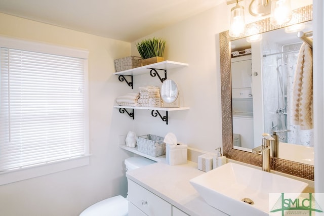 bathroom featuring stacked washer / drying machine, vanity, toilet, and a shower with shower curtain