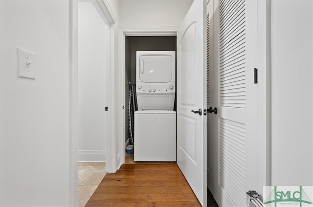 hallway featuring stacked washer / dryer and hardwood / wood-style floors