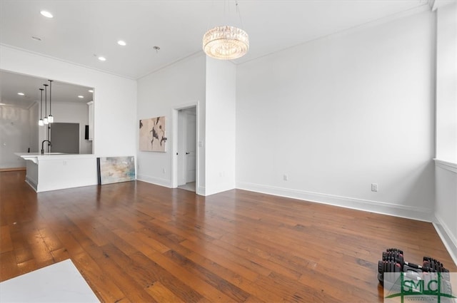 unfurnished living room featuring sink, dark wood-type flooring, and a notable chandelier