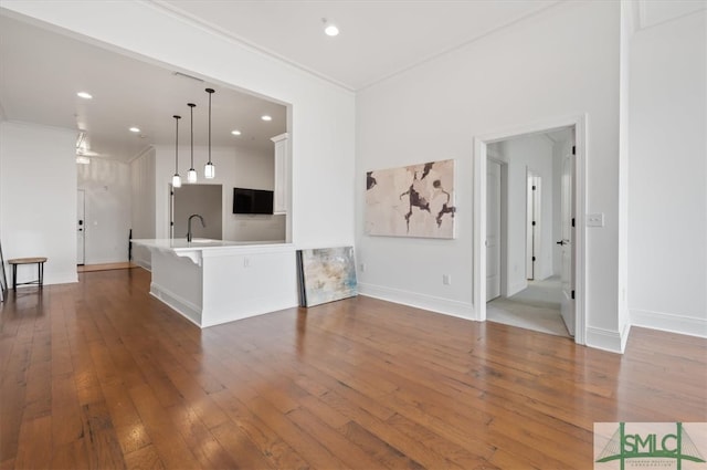 unfurnished living room featuring ornamental molding, dark hardwood / wood-style floors, and sink