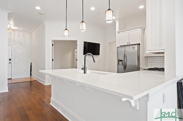 kitchen featuring white cabinetry, kitchen peninsula, pendant lighting, stainless steel appliances, and dark hardwood / wood-style floors