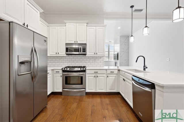 kitchen featuring appliances with stainless steel finishes, white cabinetry, dark wood-type flooring, and pendant lighting