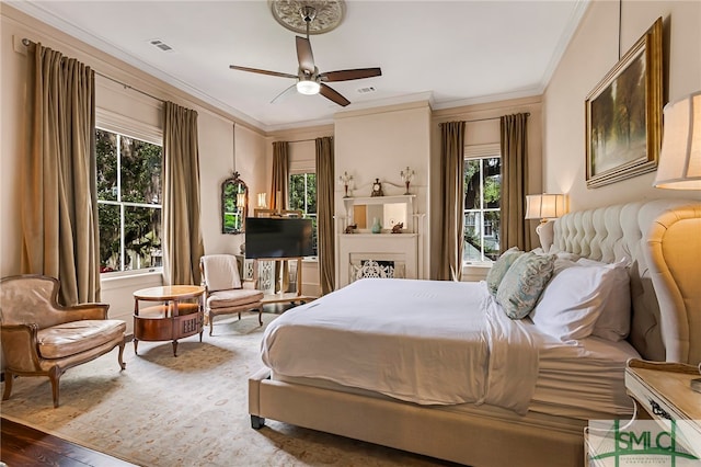 bedroom featuring multiple windows, wood-type flooring, ornamental molding, and ceiling fan