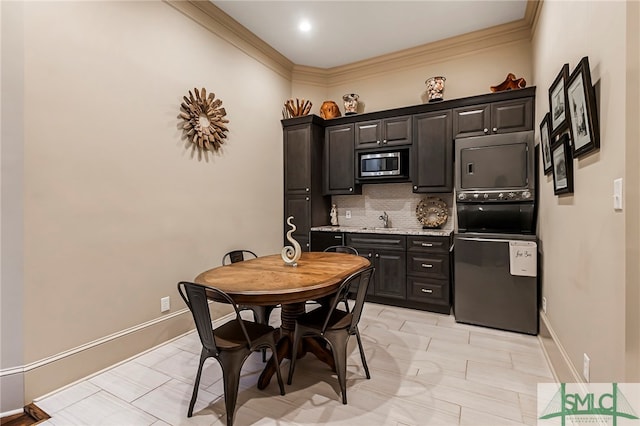 kitchen with light stone counters, tasteful backsplash, stainless steel appliances, ornamental molding, and sink