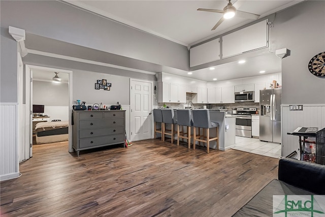 kitchen featuring white cabinetry, a breakfast bar, kitchen peninsula, stainless steel appliances, and light wood-type flooring