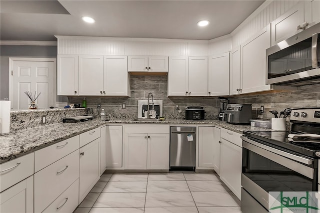 kitchen with tasteful backsplash, sink, white cabinets, appliances with stainless steel finishes, and crown molding