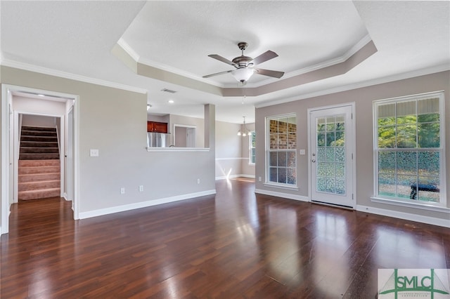 unfurnished living room with ceiling fan with notable chandelier, a raised ceiling, ornamental molding, and dark hardwood / wood-style flooring