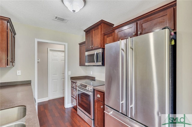 kitchen featuring stainless steel appliances, a textured ceiling, dark wood-type flooring, and sink