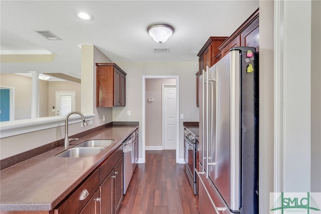 kitchen with sink, a textured ceiling, stainless steel appliances, dark hardwood / wood-style floors, and ornate columns