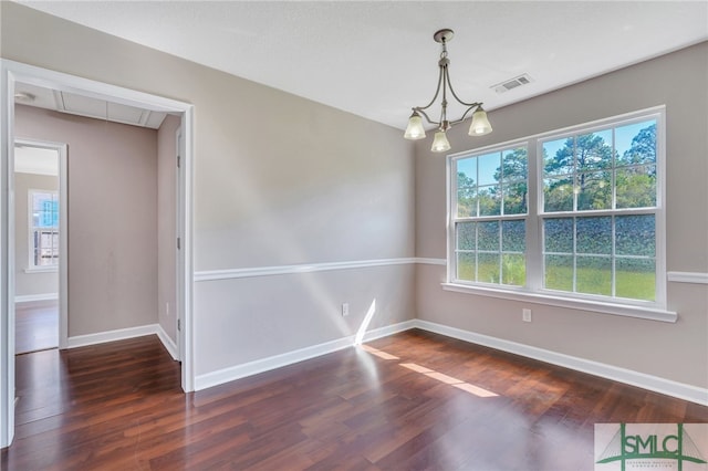 spare room with a notable chandelier and dark hardwood / wood-style floors