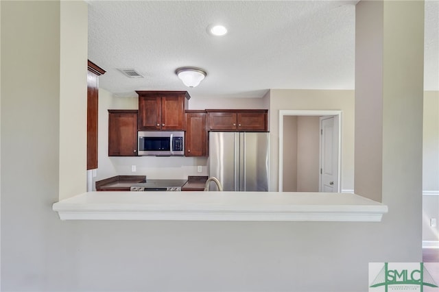 kitchen with a textured ceiling, stainless steel appliances, sink, and kitchen peninsula