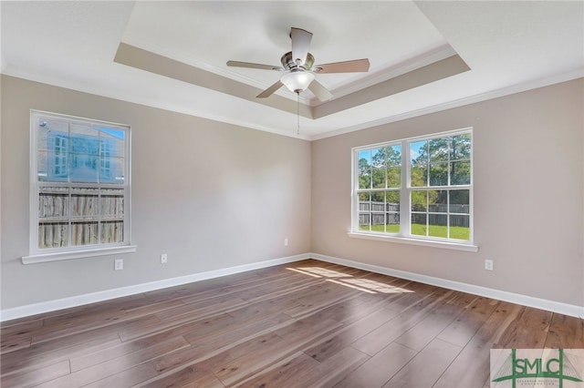 unfurnished room with ornamental molding, ceiling fan, a raised ceiling, and dark hardwood / wood-style floors