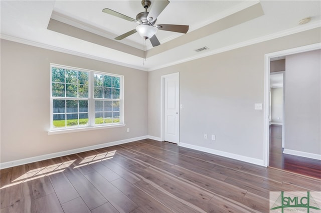 unfurnished room with a tray ceiling, hardwood / wood-style flooring, and crown molding