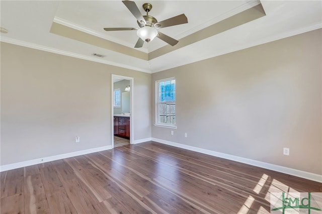 empty room featuring ceiling fan, a raised ceiling, hardwood / wood-style floors, and crown molding