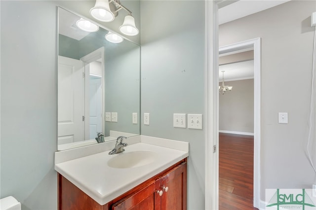 bathroom with ornamental molding, a chandelier, hardwood / wood-style flooring, and vanity